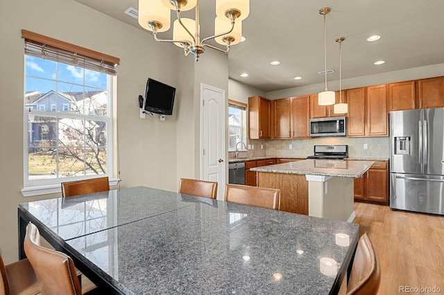 kitchen featuring stainless steel appliances, a kitchen island, hanging light fixtures, and plenty of natural light