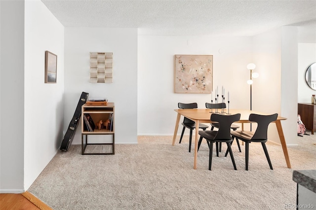 dining area featuring baseboards, carpet floors, and a textured ceiling