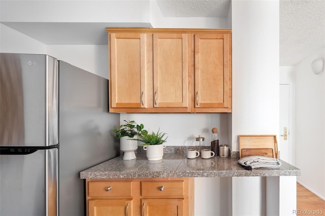 kitchen with a textured ceiling, tile counters, and freestanding refrigerator