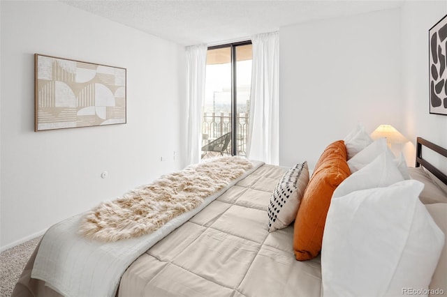 carpeted bedroom featuring expansive windows, a textured ceiling, and access to outside