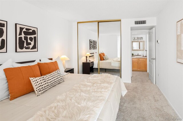 bedroom with a sink, visible vents, a closet, and light carpet