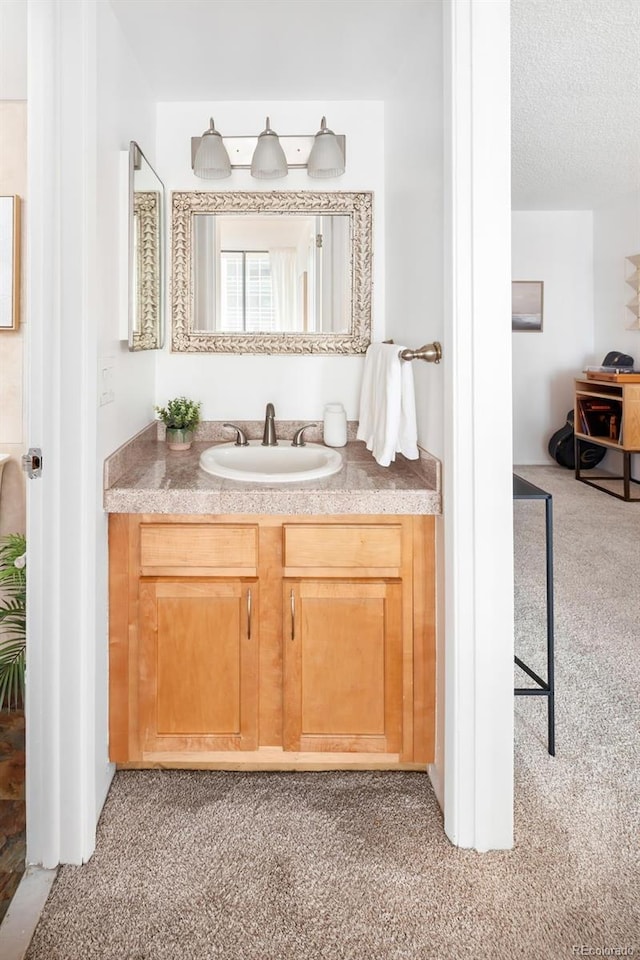 bathroom with a textured ceiling, vanity, and carpet