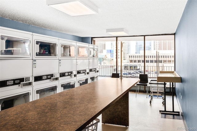 kitchen featuring oven, a textured ceiling, stacked washer / dryer, a wall of windows, and baseboards