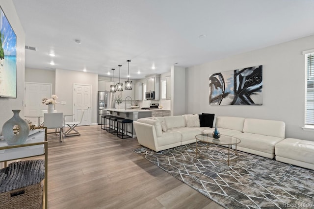 living room featuring light wood-style floors, recessed lighting, and baseboards