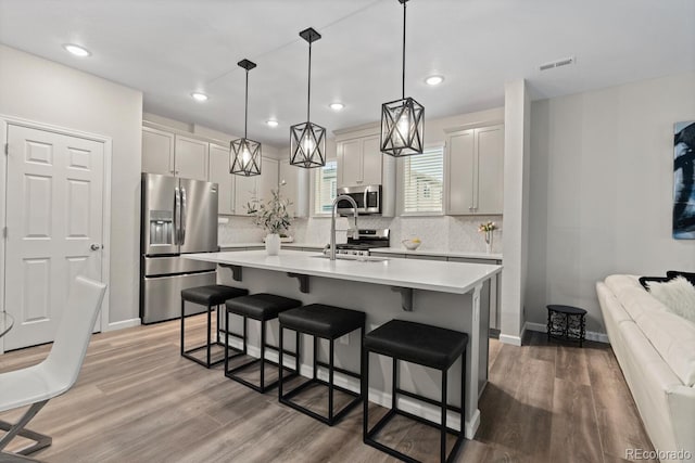 kitchen featuring appliances with stainless steel finishes, a kitchen breakfast bar, a sink, light countertops, and light wood-type flooring