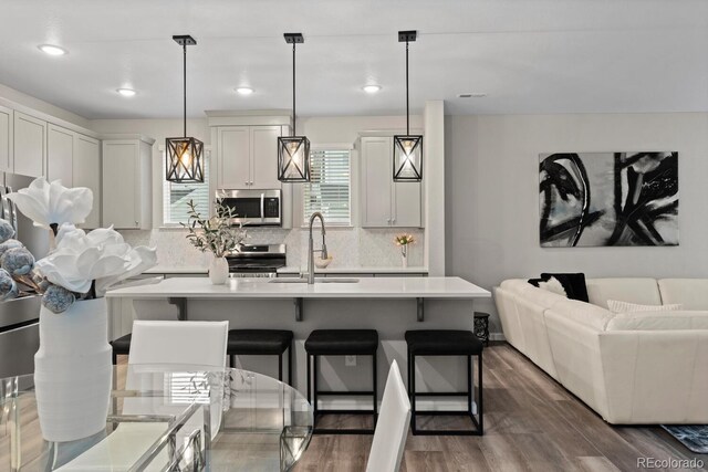 kitchen featuring appliances with stainless steel finishes, a sink, light countertops, tasteful backsplash, and recessed lighting