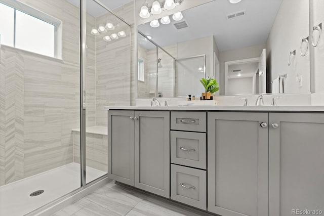 bathroom with a shower stall, marble finish flooring, and double vanity
