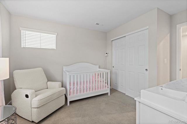 carpeted bedroom with a closet and a crib