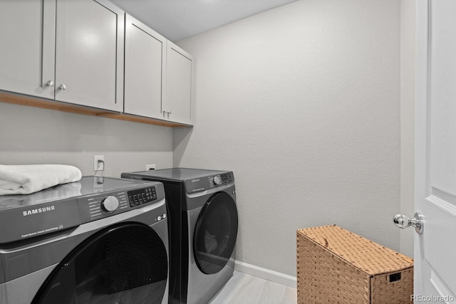 clothes washing area with cabinet space, washing machine and dryer, and baseboards