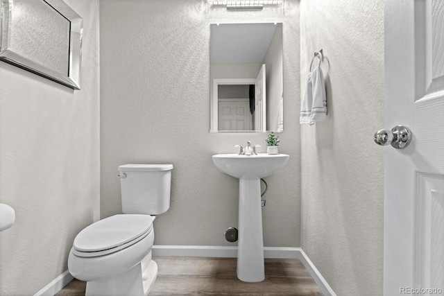 half bath with wood finished floors, toilet, and baseboards