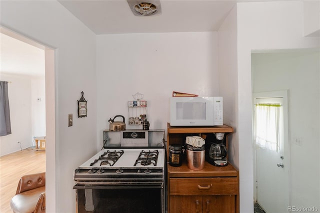 2665 W College Ave, Denver, CO 80219 - kitchen with white microwave, gas range oven, and wood finished floors