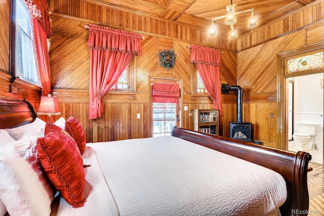 bedroom with wooden ceiling, ensuite bath, a wood stove, and wooden walls