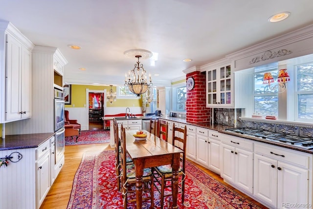 kitchen with glass insert cabinets, dark countertops, white cabinetry, and light wood-style floors