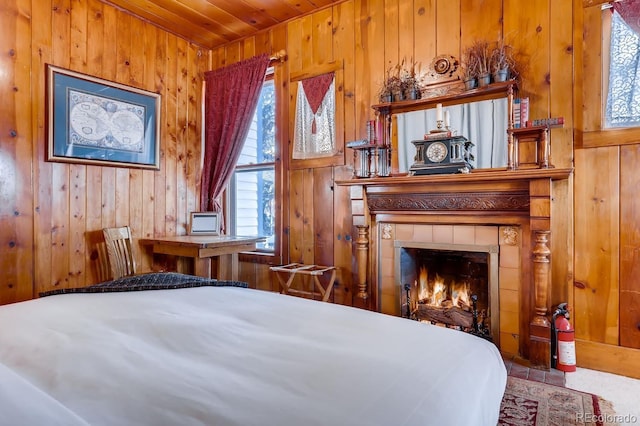 bedroom featuring wooden ceiling, wood walls, and a tile fireplace