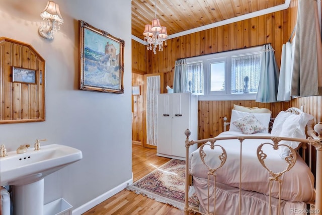 bedroom featuring a notable chandelier, wood ceiling, wooden walls, wood finished floors, and baseboards