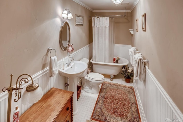 bathroom featuring ornamental molding, a soaking tub, a wainscoted wall, and toilet