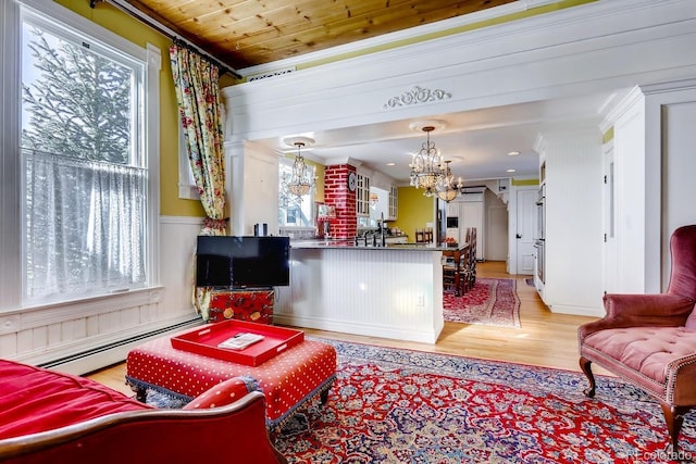 living area featuring a notable chandelier, a baseboard heating unit, wood ceiling, light wood finished floors, and crown molding