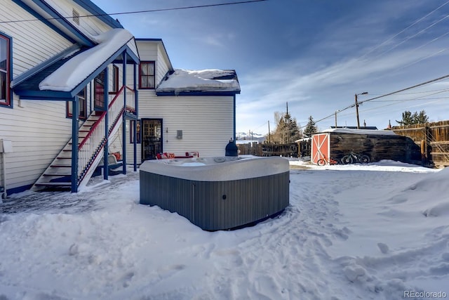 yard covered in snow featuring stairway, fence, and a hot tub