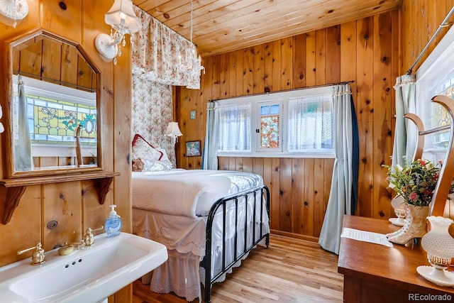 bedroom with wooden ceiling, multiple windows, a sink, and wood walls