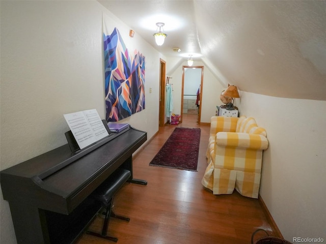 interior space featuring lofted ceiling, baseboards, and wood finished floors