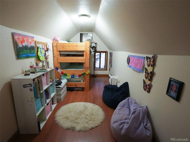 bedroom with radiator, vaulted ceiling, and wood finished floors