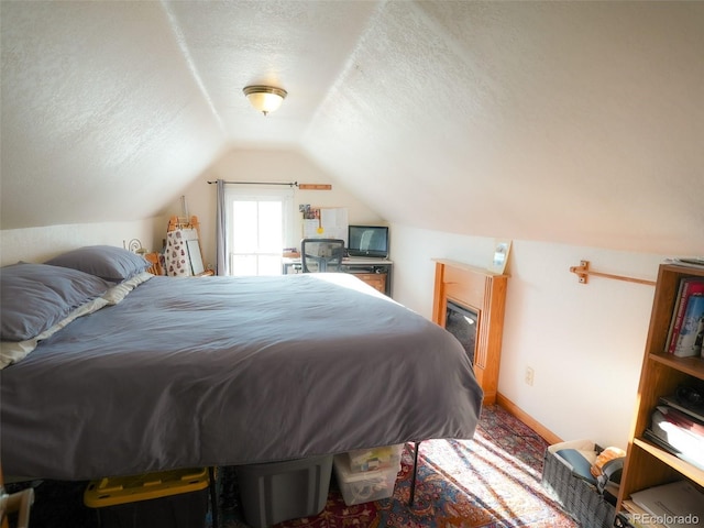 bedroom with lofted ceiling, baseboards, and a textured ceiling