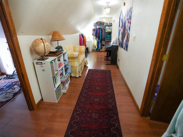 corridor with vaulted ceiling, wood finished floors, and baseboards