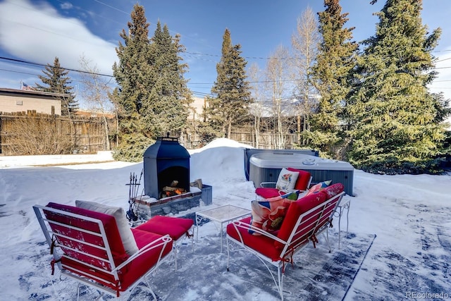 snow covered patio with an outdoor living space with a fireplace and fence