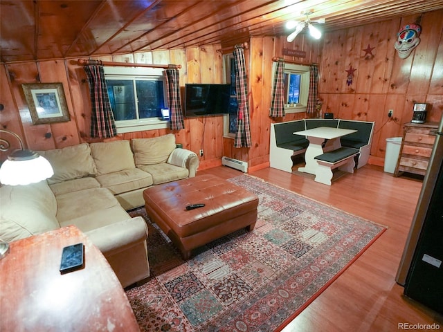 living room featuring wood walls, a baseboard heating unit, and wood finished floors