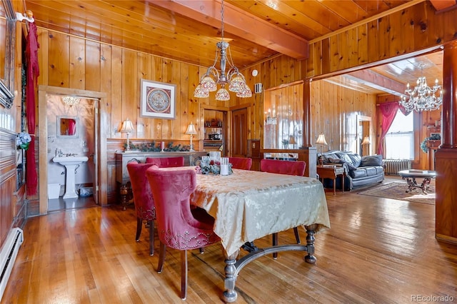 dining room featuring a baseboard radiator, radiator, an inviting chandelier, wooden walls, and hardwood / wood-style floors