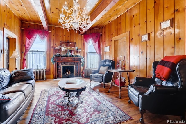 living area featuring wooden walls, radiator, wood finished floors, beam ceiling, and a high end fireplace