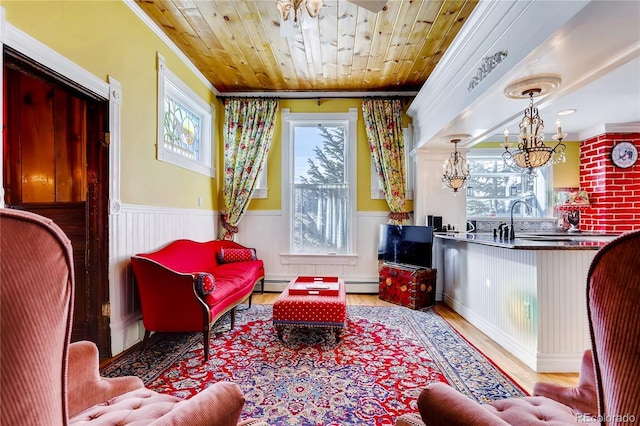 sitting room with wooden ceiling, baseboard heating, and a wainscoted wall