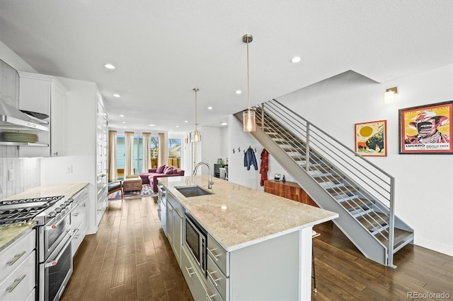 kitchen featuring white cabinetry, an island with sink, sink, and decorative light fixtures