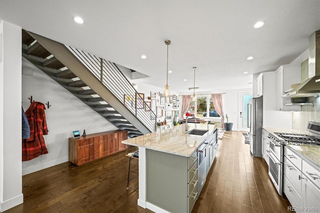 kitchen with a kitchen island with sink, wall chimney exhaust hood, white cabinets, and appliances with stainless steel finishes