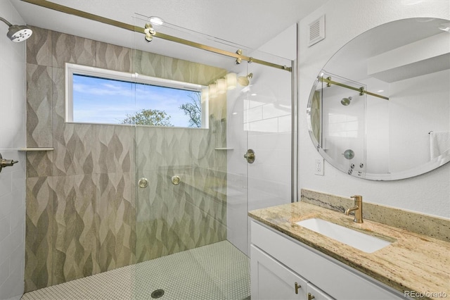 bathroom with vanity and tiled shower