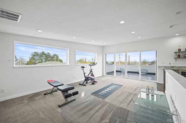 exercise area with indoor wet bar and a textured ceiling