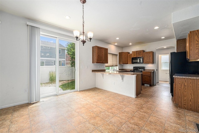 5572 Killarney St, Denver, CO 80249 - kitchen featuring black appliances, a peninsula, brown cabinetry, recessed lighting, and a kitchen bar