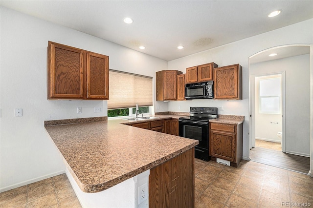 5572 Killarney St, Denver, CO 80249 - kitchen featuring black appliances, a peninsula, arched walkways, recessed lighting, and brown cabinets
