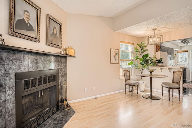 8168 Washington St Unit 46, Denver, CO 80229 - dining space featuring a textured ceiling, light wood-style floors, a fireplace, a chandelier, and baseboards