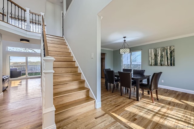 stairs with baseboards, wood finished floors, and ornamental molding