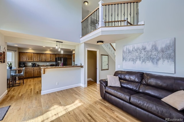 living area featuring light wood finished floors, baseboards, recessed lighting, and stairway