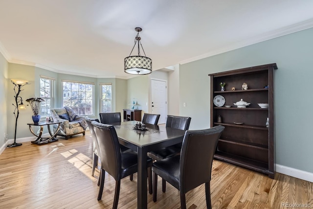 dining area featuring baseboards, ornamental molding, and light wood-style flooring