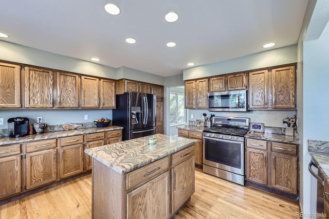 kitchen featuring light stone countertops, a center island, light wood-style floors, and appliances with stainless steel finishes