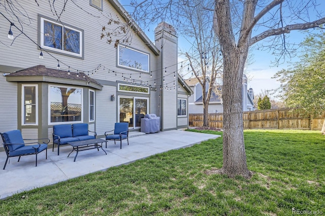 back of property featuring a chimney, fence, outdoor lounge area, a yard, and a patio