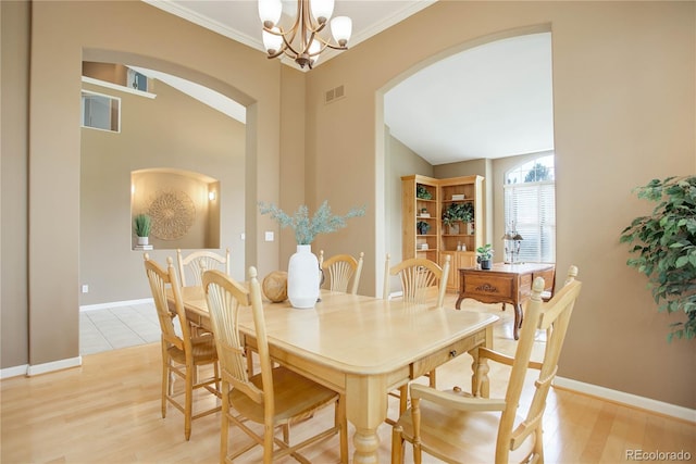 dining room featuring vaulted ceiling, a notable chandelier, ornamental molding, and light hardwood / wood-style flooring