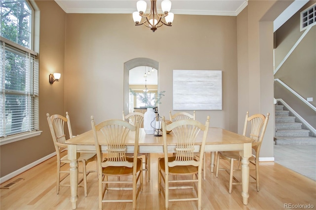 dining area featuring light wood-type flooring, a wealth of natural light, and crown molding