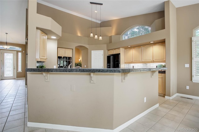 kitchen featuring a kitchen breakfast bar, light tile patterned flooring, black appliances, and decorative light fixtures