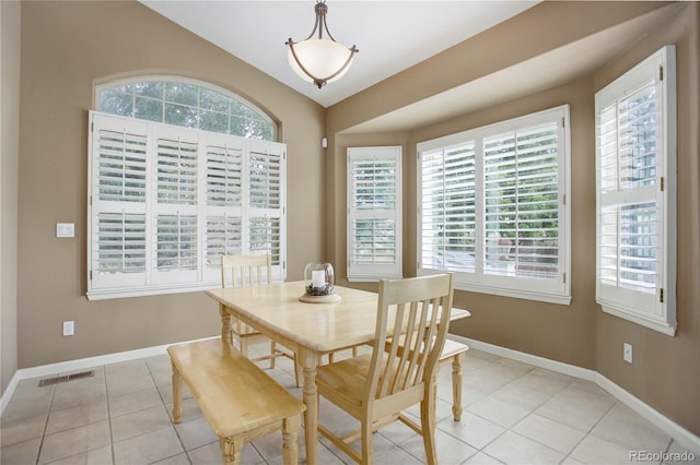 dining room featuring plenty of natural light, light tile patterned floors, and vaulted ceiling