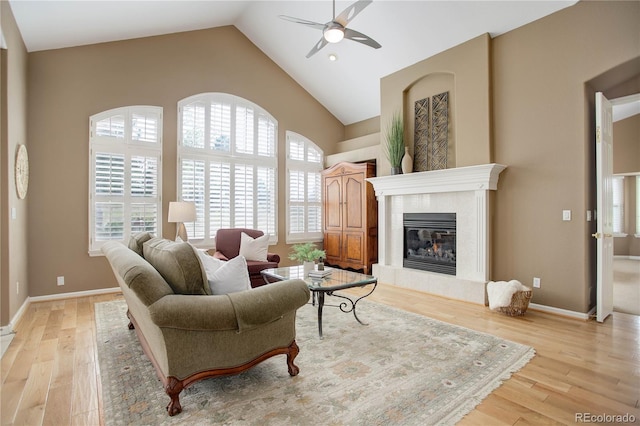 living room featuring light wood-type flooring, vaulted ceiling, a tile fireplace, and plenty of natural light