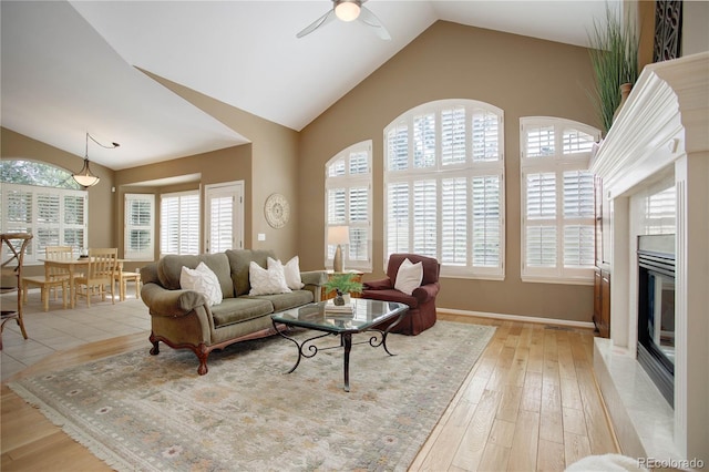 living room featuring light wood-type flooring, ceiling fan, vaulted ceiling, and a premium fireplace